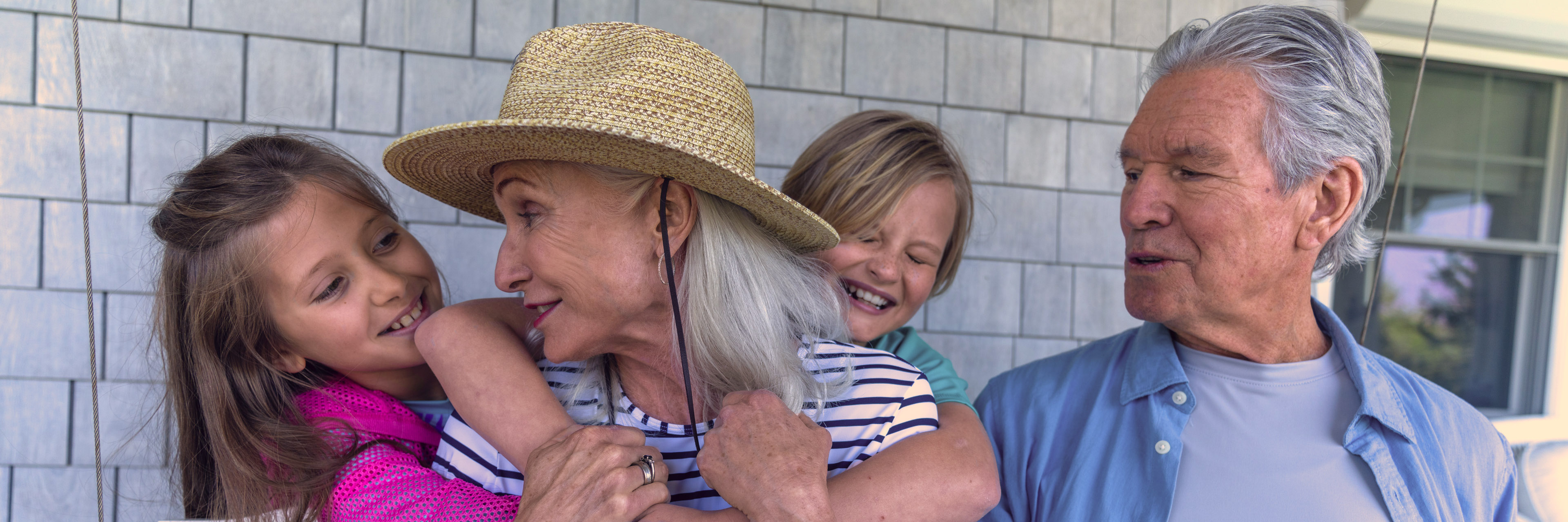 Grandparents sit with their kids on a porch. 