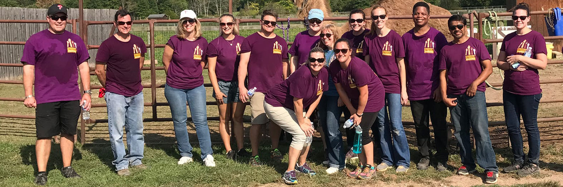 A large group of Penn Mutual associates, in purple shirts, posing together on a farm.